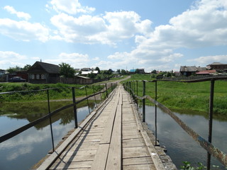 Fototapeta na wymiar Suspension bridge over the Utka river, Novoutkinsk village, Sverdlovskaya oblast, Russia