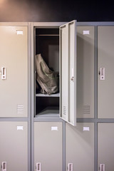 Grey and green sport bag sitting in locker room with opened door.