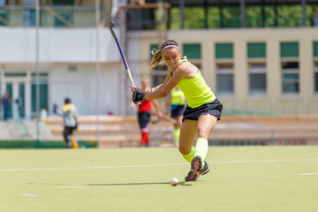 Young hockey player hit the ball in field hockey game