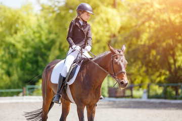 Teenage girl riding bay horse performing dressage test on equestrian competition