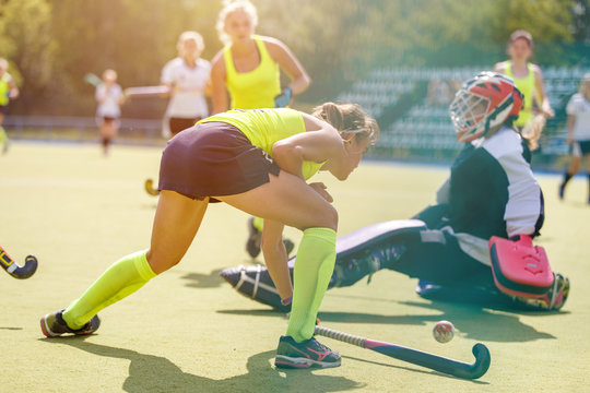 Young girl lead the ball into the net behind goalier in field hockey match