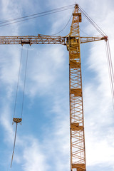 yellow tower crane on construction site against blue sky 