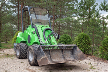 Small green tractor or skid loader parked in forest