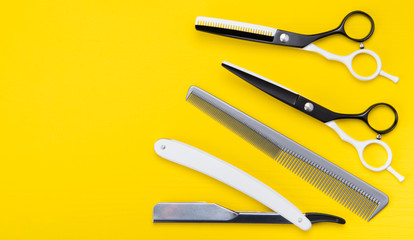 bright yellow background. a set of items for cutting hair, scissors, and combs, and dangerous razors.