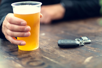 Mann trinkt Bier und Autoschlüssel liegen auf dem Tisch. Konzept des Autofahrens nach Alkoholkonsum.