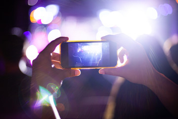 People taking photographs with smart phone during Live music concert and crowd in background