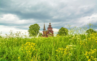 Ancient wooden church on a summer meadow among the flowers