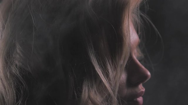 Attractive blonde girl in white thick smoke cloud, closeup portrait shot in slowmotion, dark background, 150fps