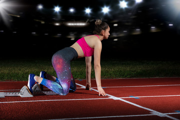 woman sprinter leaving starting blocks on the athletic track. exploding start on stadium with...