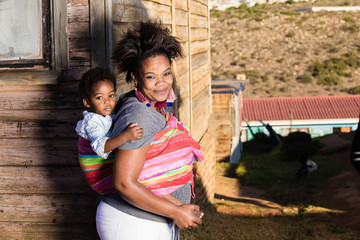 Mother and child standing infront of a shack