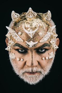 Man with golden reptilian skin and white beard. Monster with sharp thorns and warts on face, horror and fantasy concept. Demon head with evil look on black background