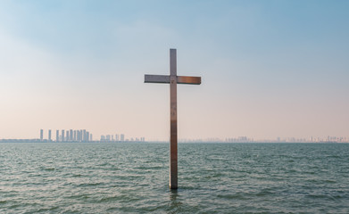 Metal christian cross in the water over blue sky background