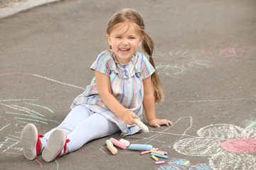 Fototapeta premium Cute little girl drawing with chalk on asphalt