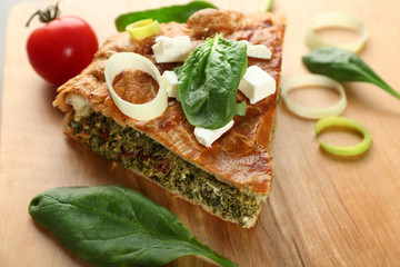 Piece of tasty pie with spinach on wooden table
