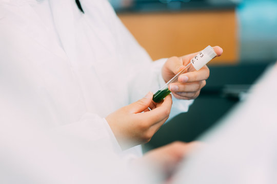 student holds a vile of liquid in lab