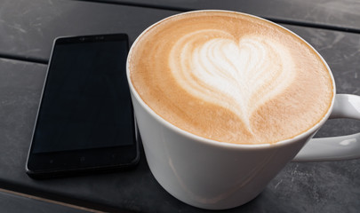 technology, business and modern life concept- close up of smartphone and coffee cup on table at cafe