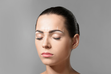 Young woman before procedure of eyebrows permanent makeup on grey background - obrazy, fototapety, plakaty