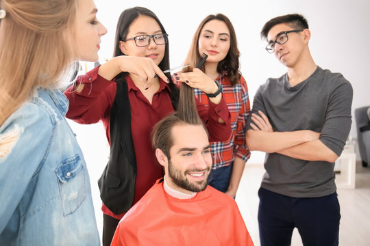 Professional hairdresser and trainees working with client in salon. Apprenticeship concept