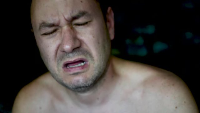 A man tortures himself, beating himself on the cheeks and head.