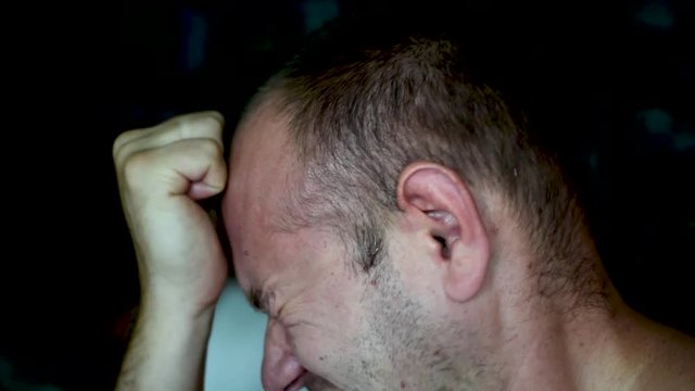 A man tortures himself, beating himself on the cheeks and head.