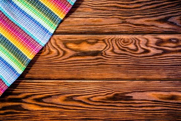     The colorful tablecloth is a brown wooden table 
