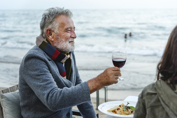 Seniors toasting with red wine at the beach