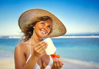 Smiling woman putting on sunscreen
