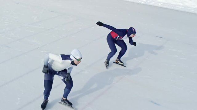 High angle view of two professional sportsmen starting speed skating race on outdoor ice rink in winter