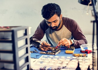 Technician using multimeter with computer electronics parts