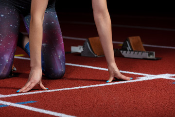 woman sprinter leaving starting blocks on the athletic track. exploding start on stadium with...