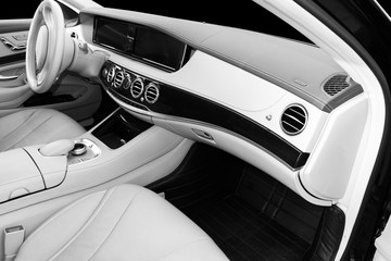 White leather interior of the luxury modern car. Leather comfortable white seats and multimedia. Steering wheel and dashboard. Automatic gear shift. Car interior. Car detailing. Black and white