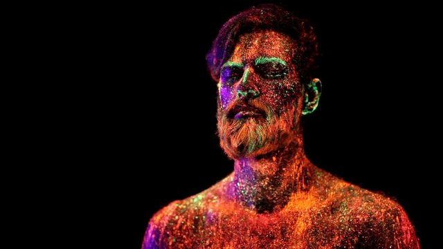 Concept. Portrait of a bearded man. The man is painted in ultraviolet powder