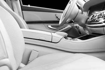 White leather interior of the luxury modern car. Leather comfortable white seats and multimedia. Steering wheel and dashboard. Automatic gear shift. Car interior details. Black and white