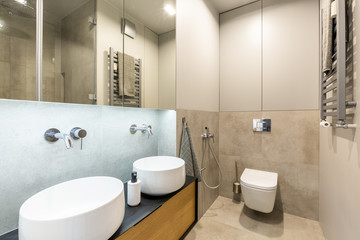 Fototapeta na wymiar Stylish, modern ensuite bathroom interior with beige marble tiles, big mirror and two washbasins for a couple
