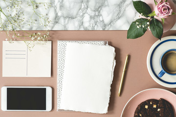 Top view on white paper with copy space and smartphone on desk with pink rose. Real photo