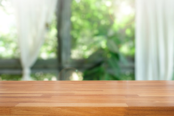 Empty of wood table top on blur of abstract green from garden with sunlight and curtain window