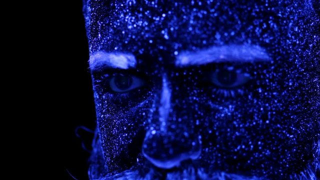 Concept. Portrait of a bearded man. The man is painted in ultraviolet powder