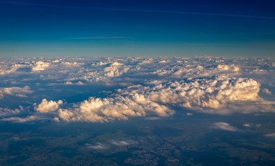 View from airplane window showing clouds and mountains in central europe.