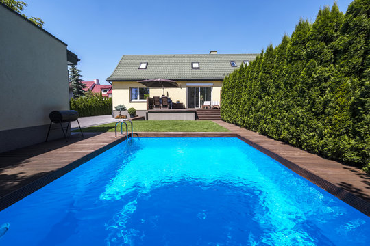 Swimming pool in the garden of house with trees during summer. Real photo