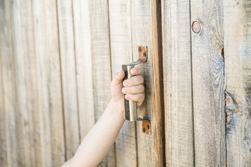 a child's hand holding a handle and trying to open a wooden door
