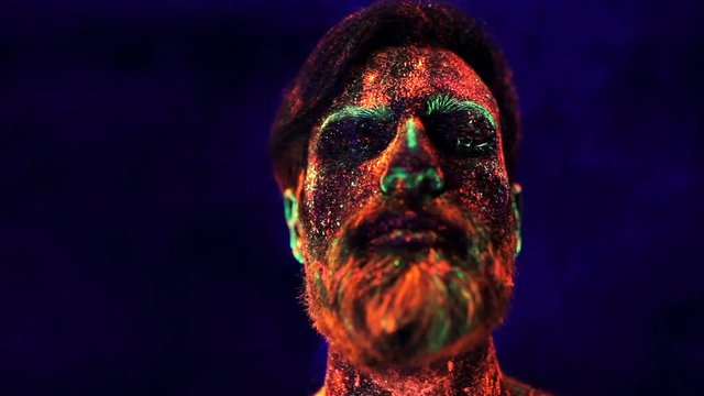 Portrait of a bearded man in ultraviolet light in smoke