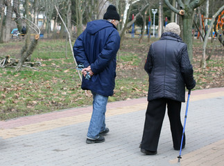 Old elderly man and woman walking with a cane