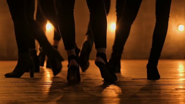 Close up Silhouettes of dancing girls. go-go dance. Closeup dance performance of pretty female group on a dark stage with yellow lights. team dance of women in high heels. 1080 slow motion