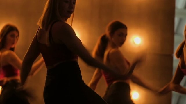 close up silhouettes of dancing girls. go-go dance. Closeup dance performance of pretty female group on a dark stage with yellow lights. team dance of women in high heels. slow motion