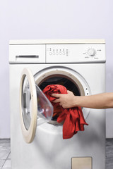 Man hands put the clothes into washing machine