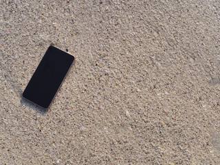 Mobile smart phone on the sandy beach with soft waves of sea background.  Internet of thing concept.