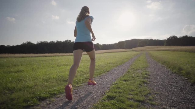 slow motion following woman running on gravel road in summer
