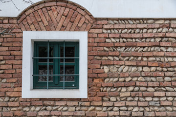 grünes Fenster inmitten einer Ziegelmauer