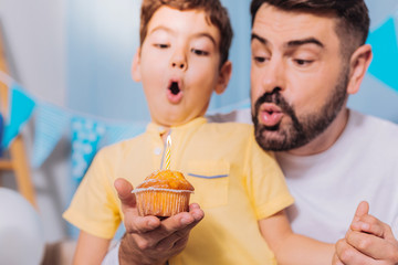 Just do it. Serious boy opening mouth while blowing out candle