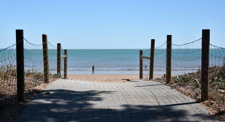 Fototapeta premium Sea beach wooden walkway path entrance. Sandy ocean beach entrance to Mindil beach, Darwin, Northern Territory of Australia.